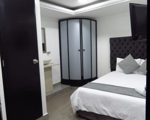 a bedroom with a large bed and a bathroom at Inizio Hotel Boutique Laureles in Medellín