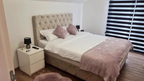 Un dormitorio con una cama con almohadas rosas. en Lilien apartment Airport en Ledine