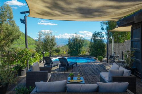 um pátio com uma piscina, cadeiras e uma mesa em AzulZenLodge em Paine