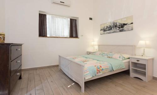 a white bedroom with a bed and a dresser at Studio stonehouse in Ičići