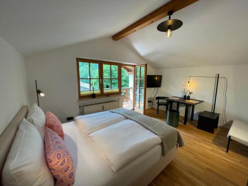 Un dormitorio con una gran cama blanca y un escritorio. en Design-Studio mit Zugspitzblick, en Grainau