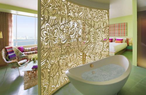 a bathroom with a bath tub and a living room at Symphony Style Hotel Kuwait in Kuwait