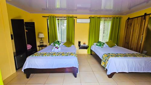 two beds in a room with green curtains at Confort Arenal in Fortuna