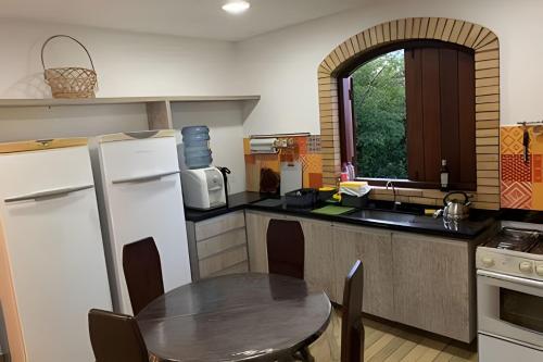 cocina con mesa, nevera y fregadero en Sítio em Aldeia com piscina e vista para o vale, en Camaragibe