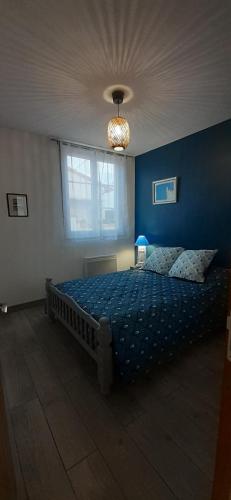 - une chambre avec un lit et un mur bleu dans l'établissement Maison pour 2 à 4 personnes avec jardin proche de la plage et des commerces ROYAN, à Royan