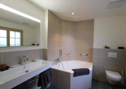 ein Badezimmer mit einer Badewanne, einem WC und einem Waschbecken in der Unterkunft Luxury Chalet Solidage in Rougemont