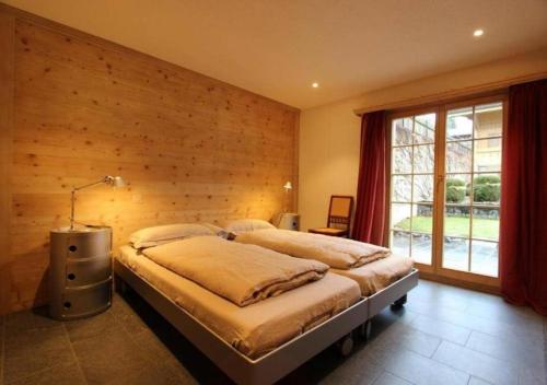 ein Schlafzimmer mit einem Bett mit einer Holzwand in der Unterkunft Luxury Chalet Solidage in Rougemont