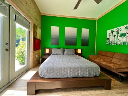 Dormitorio verde con cama y sofá en The Tatman Evergreen Suite en Lake Alfred