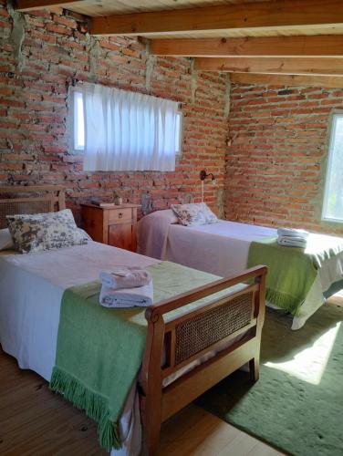 1 dormitorio con 2 camas y pared de ladrillo en La pacaa` en Bella Vista
