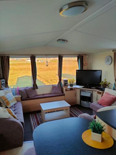 a living room with a couch and a tv at M&C Caravan Hire Sunnysands in Barmouth