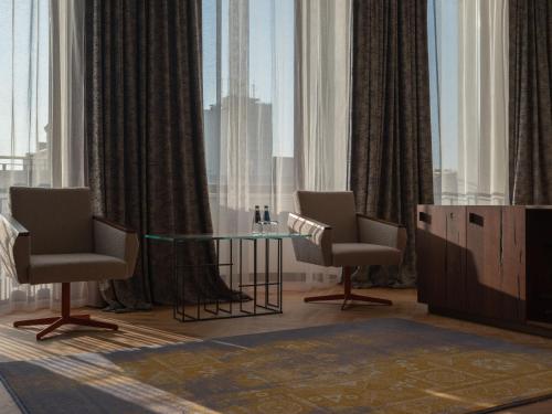 a living room with two chairs and a glass table at Grand Hotel in Łódź