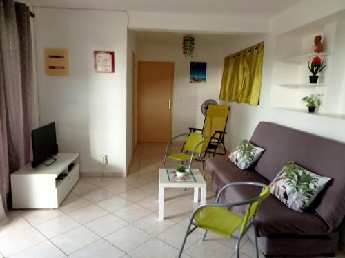 a living room with a couch and chairs and a tv at F2 proche plage Anse Mitan in Les Trois-Îlets