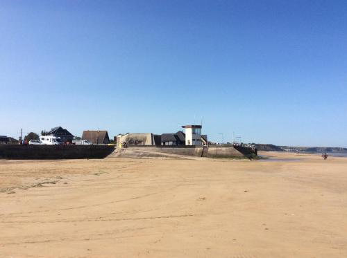 a sandy beach with a building in the background at Apt duplex ou plain pied tout confort plein centre ville Bayeux proche commerces, restaurants, avec terrasse privative ou jardin commun aménagé clos, parking gratuit à proximité, proche plages du débarquement in Bayeux