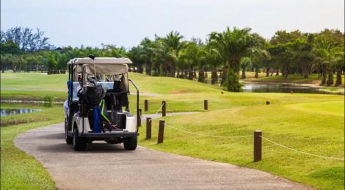 un golf cart parcheggiato su un campo da golf di New Casino, beach and golf condo at Hard Rock Punta Cana area a Punta Cana