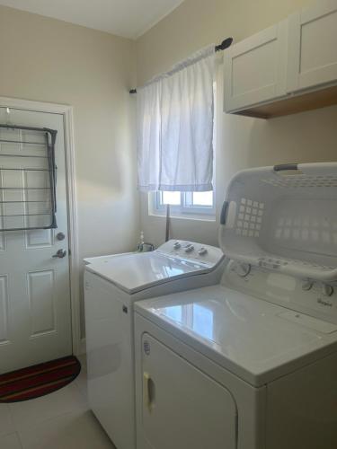 a white kitchen with a sink and a dishwasher at Seamist villa @Oceanpointe Lucea comfy 2BR w/pool gym & parking in Lucea