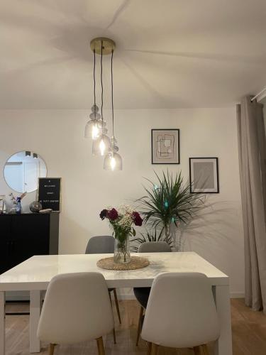 uma mesa de jantar branca com cadeiras e um vaso de flores em Appartement Cosy Beauvais em Beauvais