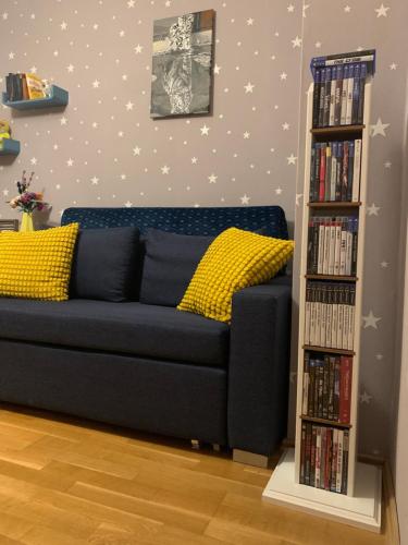 a blue couch in a room with a book shelf with dvds at Leon’s Apartment in Krefeld
