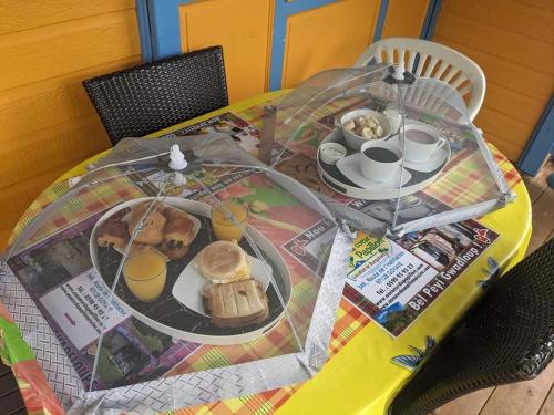 a table with a plate of food and drinks on it at Au cœur du papillon piscine privée in Goyave
