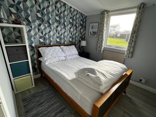 1 dormitorio con cama y ventana en Modern Funky Private Chalet at the Beach, en Tywyn