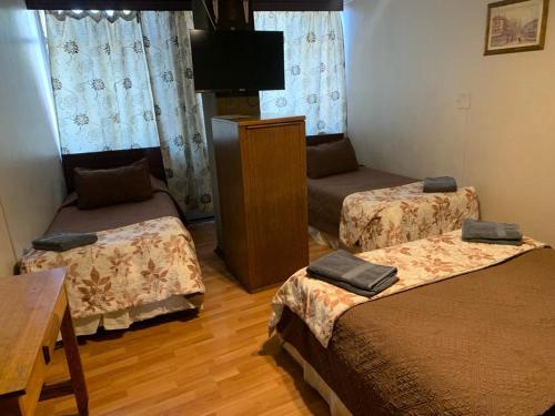 um quarto com 2 camas e uma televisão de ecrã plano em Hotel Alameda em Santiago