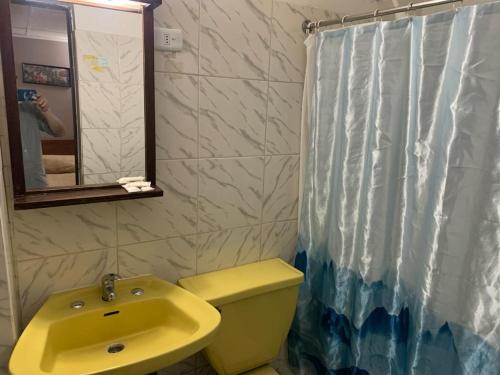 uma casa de banho com um lavatório amarelo e uma cortina de chuveiro em Hotel Alameda em Santiago