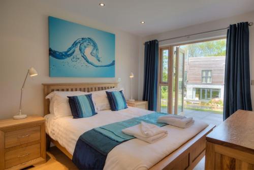 a bedroom with a bed and a large window at House 12 in Looe