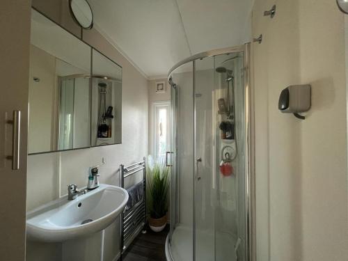 een badkamer met een wastafel en een glazen douche bij Chalet am See in Lathum