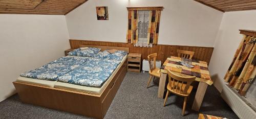 a bedroom with a bed and a table and a desk at Pension u Havrana in Jetřichovice