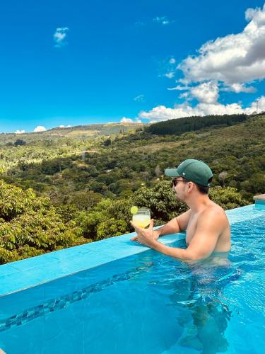 a man in a swimming pool with a drink at Hotel Campestre Palmas del Zamorano in San Gil