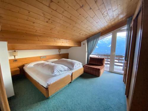 a bedroom with a bed and a chair and a window at Affittacamere Garden Cavalese in Cavalese