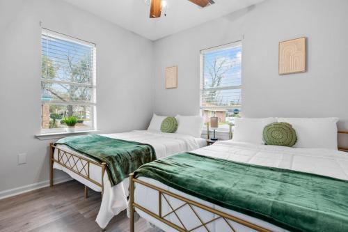 two beds in a room with white walls and windows at Near River St, Forsyth & DT - Stylish - Free Parking in Savannah