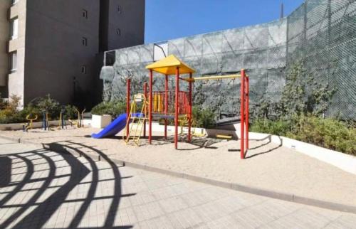 a playground in front of a building at Departamento a pasos de la salud que necesitas in Santiago