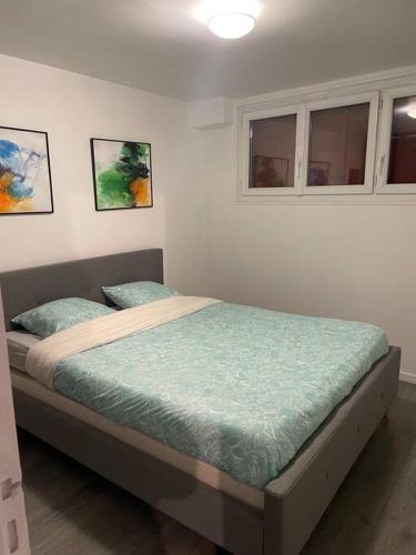 ein Bett in einem Schlafzimmer mit zwei Bildern an der Wand in der Unterkunft Porte de Paris- les Puces in Saint-Ouen