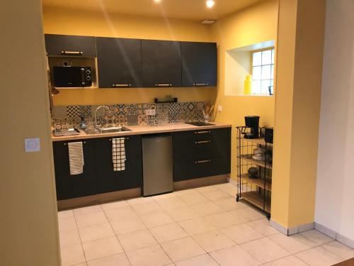 Il comprend une cuisine avec des placards noirs et du carrelage. dans l'établissement En plein coeur de Port en Bessin - Coté Port, à Port-en-Bessin-Huppain