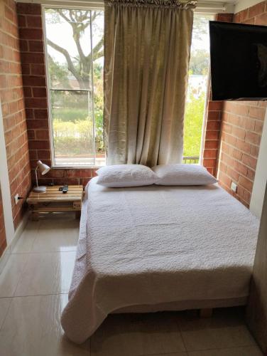 een slaapkamer met een groot bed en een raam bij A diez minutos del aeropuerto in Palmira