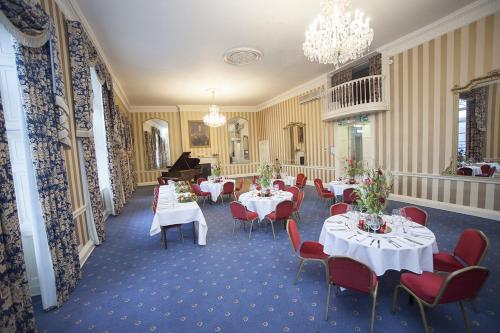 a dining room with tables and chairs and a piano at Norfolk Arms Hotel in Arundel