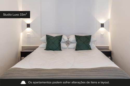una camera da letto con un letto bianco con cuscini verdi di Charlie Connect PUC a Porto Alegre