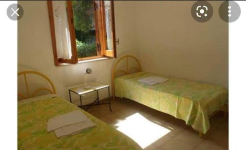 two beds in a room with a window at Condominio Smeraldo in Torre Forte