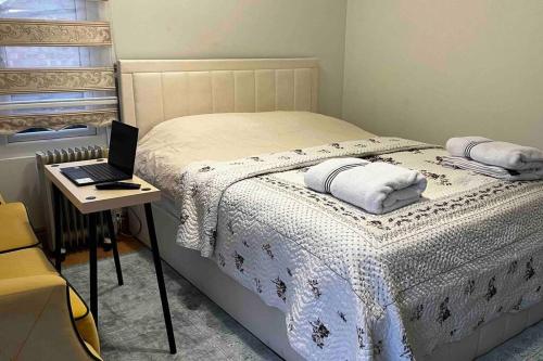 a bedroom with a bed with a laptop on a table at Charming Private Guest House in Enfield