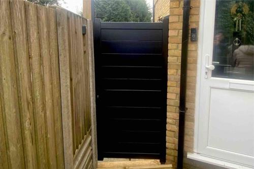 a black door leading to a wooden fence at Charming Private Guest House in Enfield