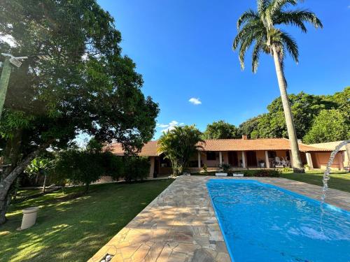 uma piscina em frente a uma casa com uma palmeira em Chácara Marretto, ambiente acolhedor e familiar dentro da cidade de Tatuí. em Tatuí