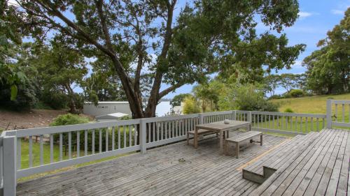 a wooden deck with a bench and a fence at Lakeview Treehouse in Metung