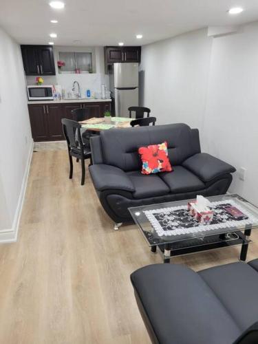 uma sala de estar com um sofá preto e uma mesa em Basement apartment, 25 Minutes to Downtown em Toronto