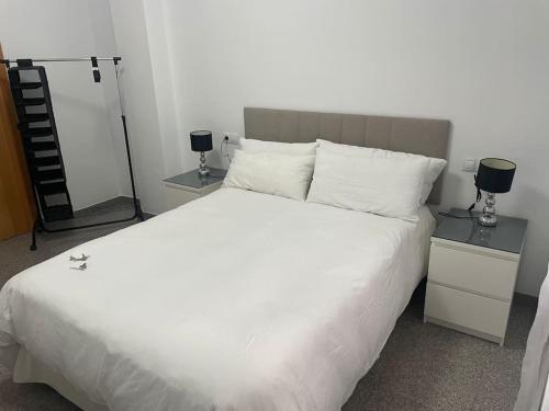 1 dormitorio con 1 cama blanca grande y 2 mesitas de noche en Casa Pérez, en Aguilar de la Frontera