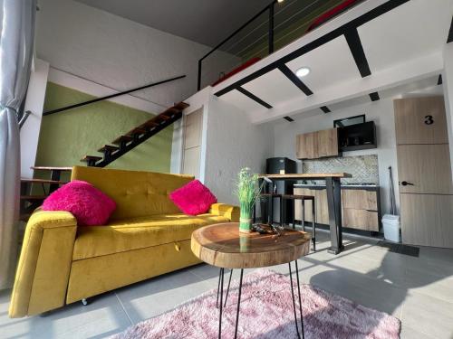 ein Wohnzimmer mit einem gelben Sofa und einem Tisch in der Unterkunft apartaestudios las astromelias salento in Salento