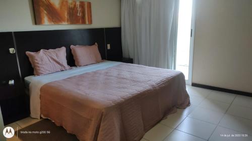 a bedroom with a large bed with pink pillows at Studio pé na areia, vista, internet e ar in Macaé