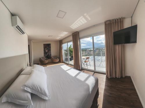 a bedroom with a large bed and a large window at Villa Verde Bangalô - Garopaba - SC in Garopaba