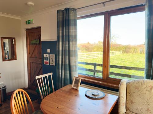 een eetkamer met een tafel en een raam bij Orchard House Lodges by Ecohuman in Haddington