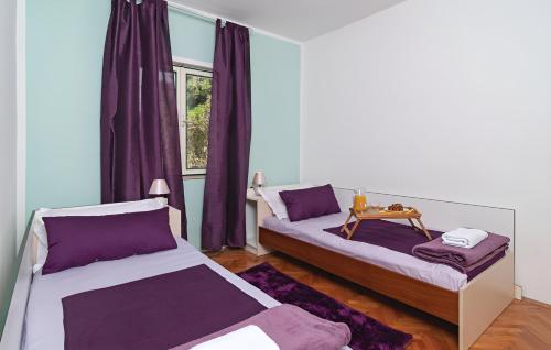 two beds in a room with purple curtains at Villa Olive Tree in Kaštela