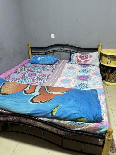 a bed with a colorful blanket and pillows on it at Faris Guest House in Sharjah